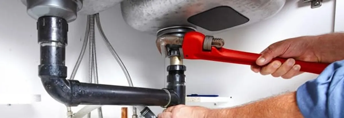 Garbage disposal repair technician tightening the sink drain and disposal connection in Raleigh, NC