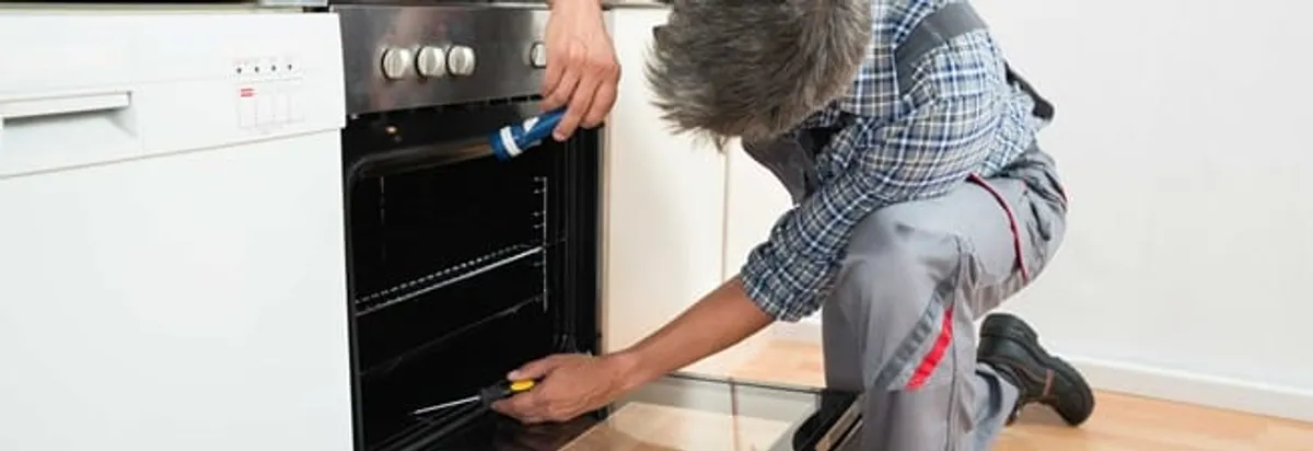 Oven repair technician inspecting and servicing an electric oven in Raleigh, NC