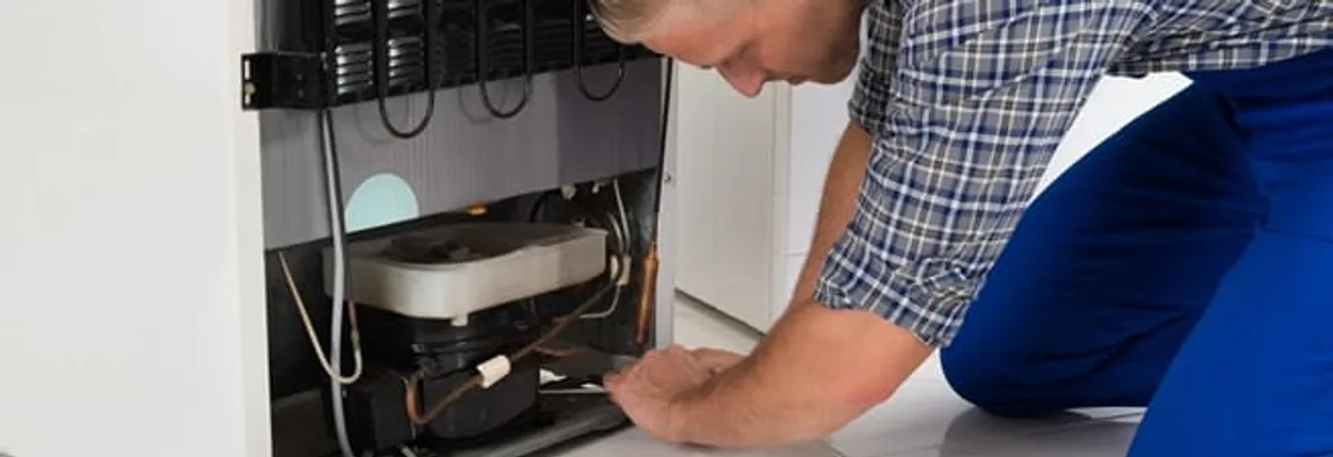 Refrigerator repair technician servicing the compressor and condenser area in Raleigh, NC