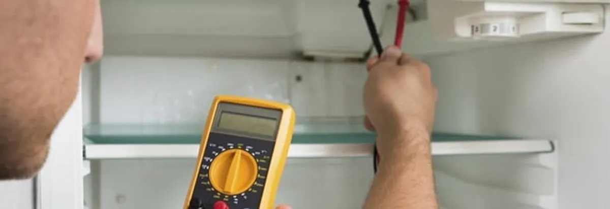 Refrigerator repair technician testing electrical components with a multimeter in Raleigh, NC