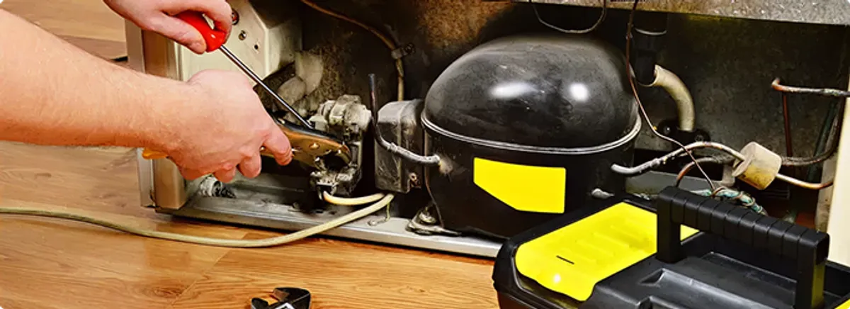 Refrigerator repair technician fixing the compressor and wiring in Raleigh, NC
