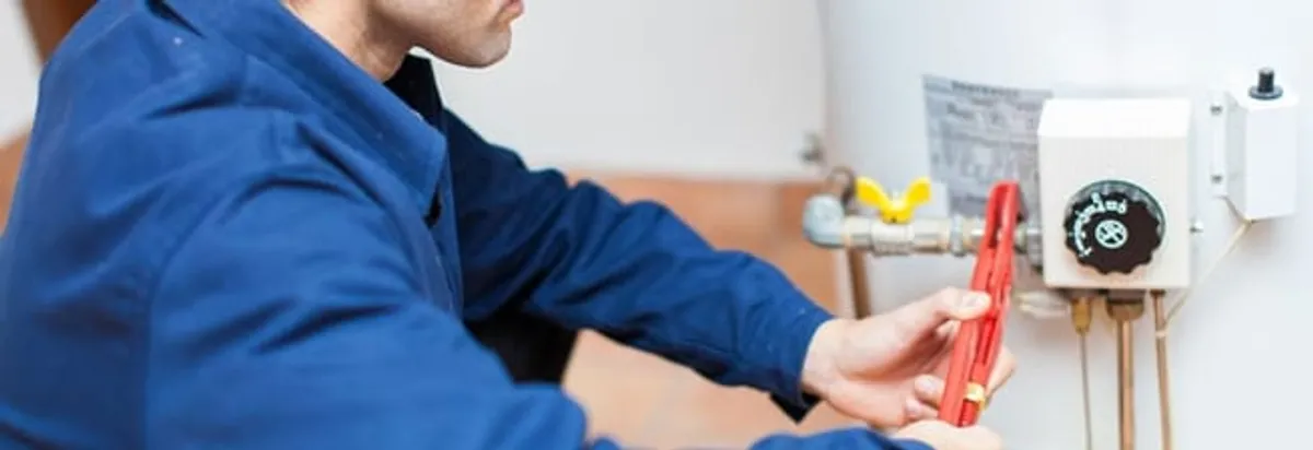 Water heater repair technician adjusting the temperature control and gas valve in Raleigh, NC